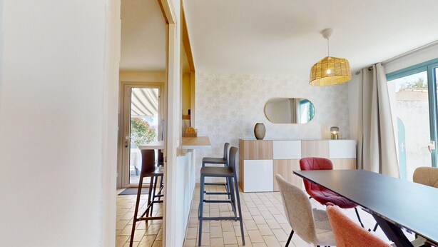 A modern dining area with a long table, chairs, and a hanging light fixture. - Villa Good Vibes - Bikes available, large fenced-in garden (Le Fenouiller)