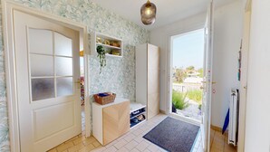 A room with a frosted glass door, a white wardrobe, a shelf with decorative items, a hanging plant, and a view through a glass door. - Villa Good Vibes - Bikes available, large fenced-in garden (Le Fenouiller)