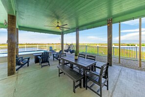Eine überdachte Terrasse im Freien mit Tisch, Stühlen und Deckenventilator.