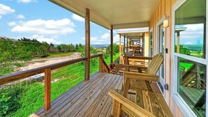 A wooden deck with a railing overlooking a grassy area and a view of the ocean. - Water Views | Wraparound Decks | Pool Access | Flour Bluff Bay | Black Drum (Corpus Christi)