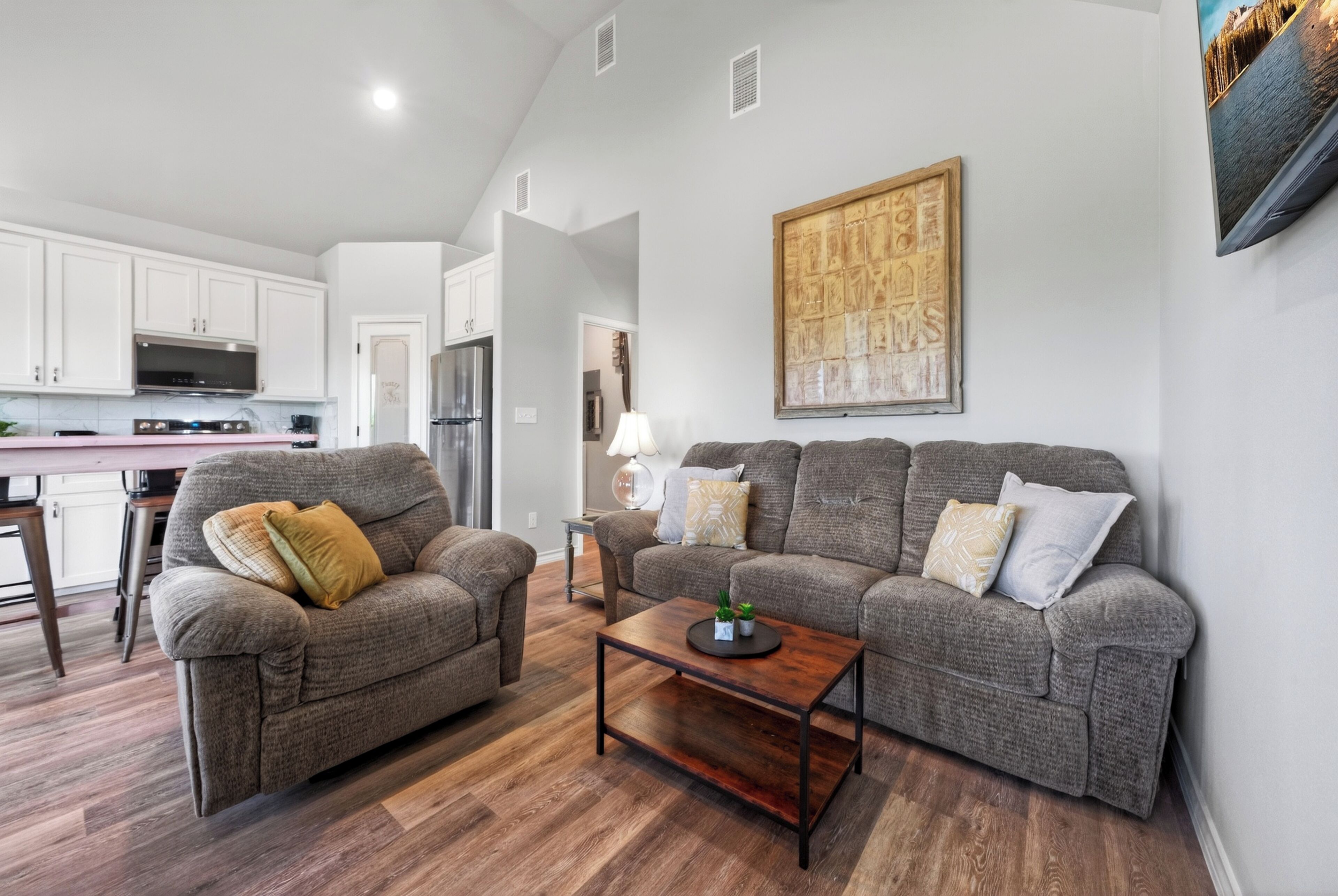 A living room with a sofa set, a coffee table, and a kitchen in the background.