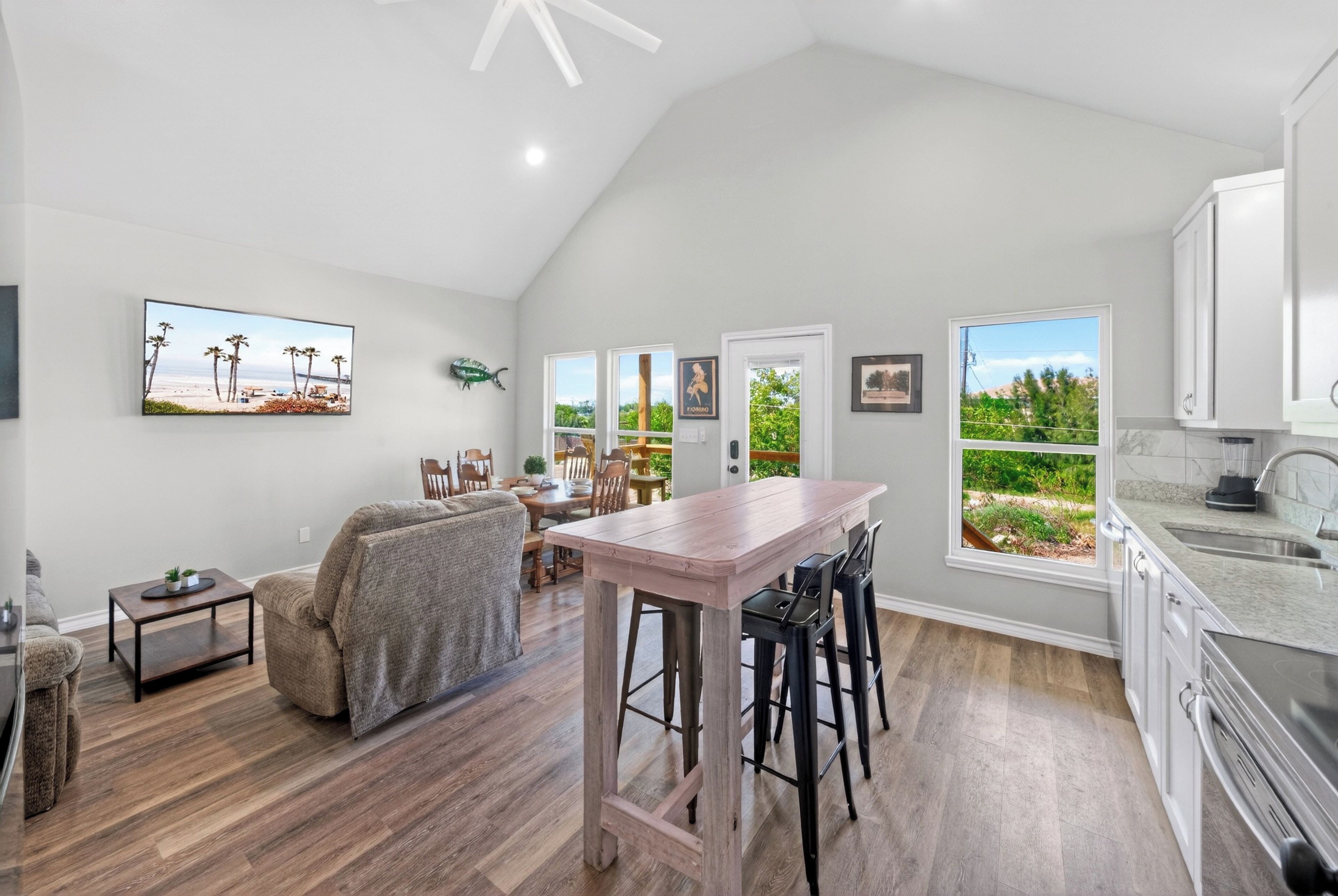 A spacious kitchen with a large island, a dining area with a view, and a living room with a couch and coffee table.