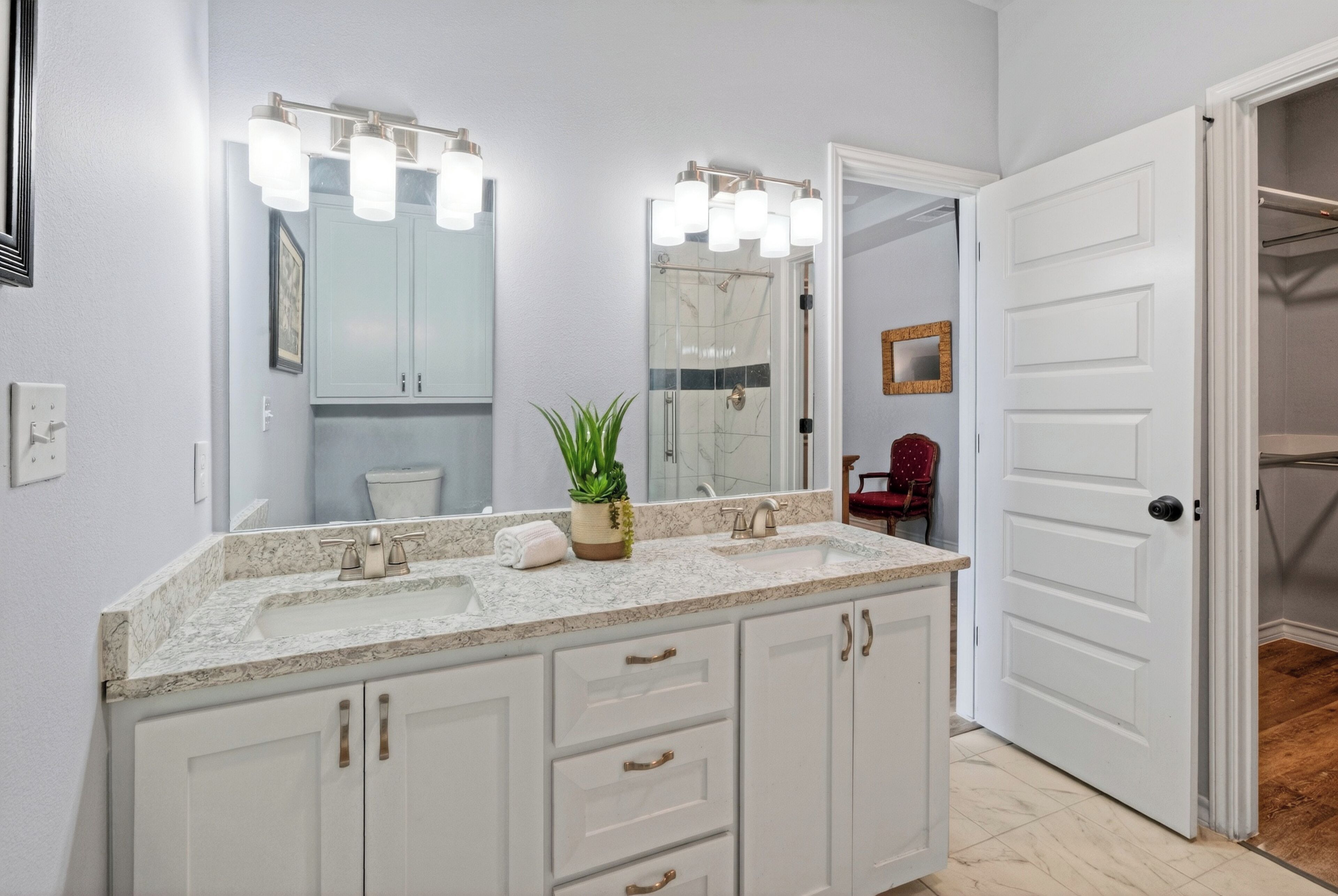 A bathroom with a double sink, a large mirror, and a shower.