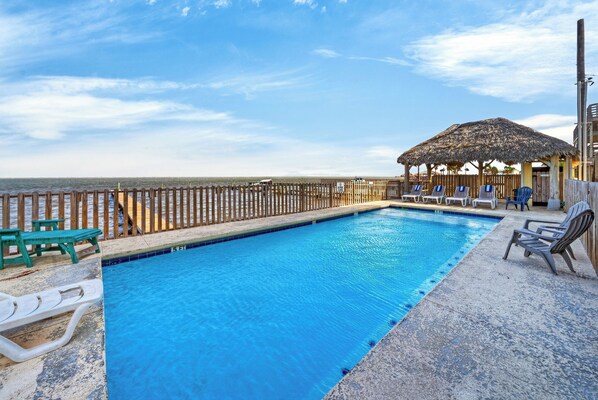 Une piscine avec des chaises longues et une terrasse en bois.