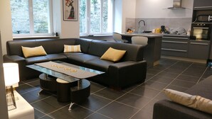 Ein modernes Wohnzimmer mit einer Couch, einem Couchtisch und einer Küchenzeile mit Geräten.
