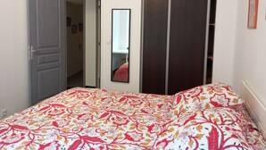 Ein Schlafzimmer mit Bett, Kleiderschrank, Spiegel und einer Tür zu einem anderen Raum.