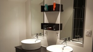 Ein modernes Badezimmer mit zwei Waschbecken, dunklen Schränken und einem großen Spiegel.