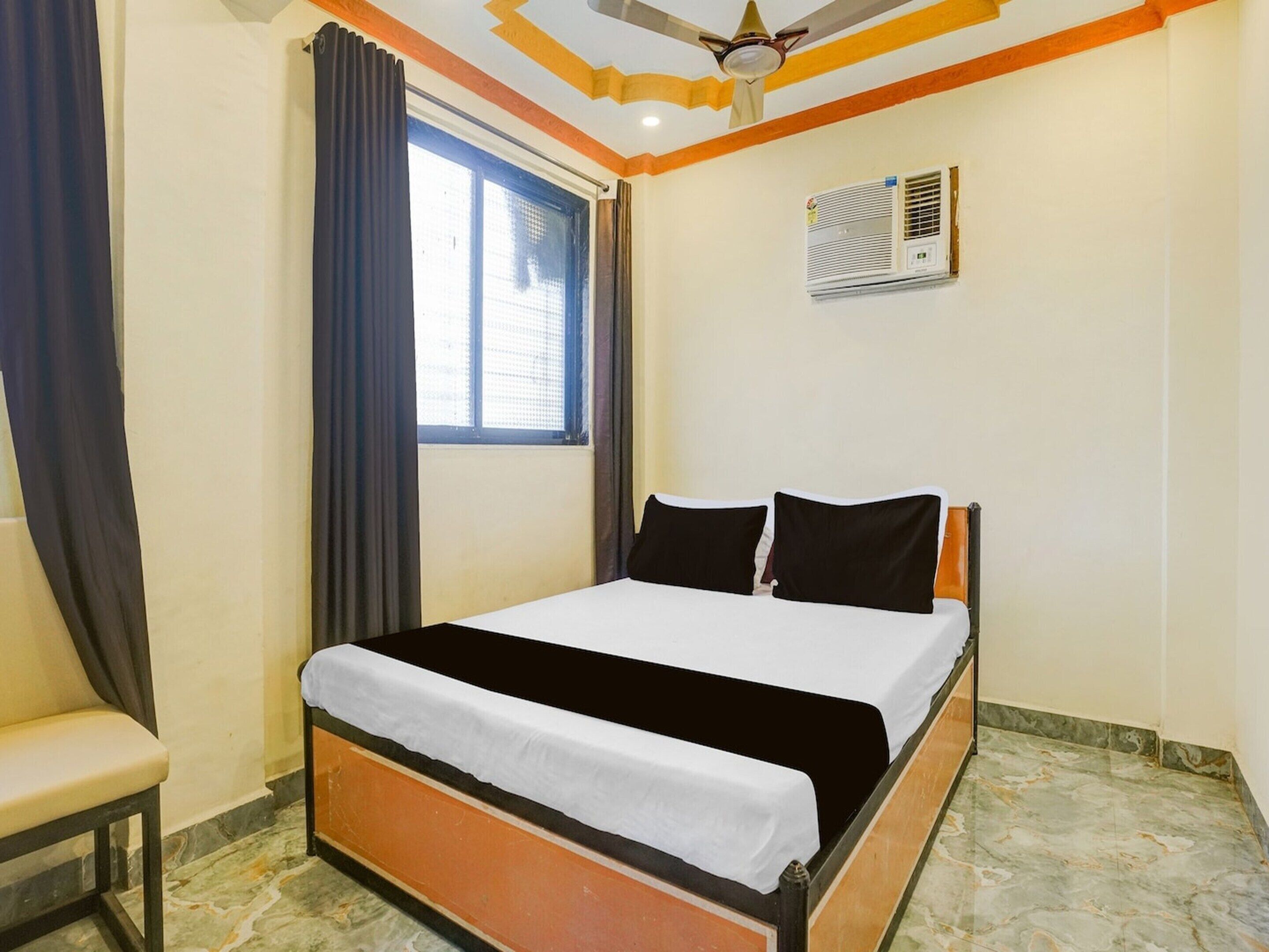 Un dormitorio con cama, ventana con cortinas, ventilador de techo y aire acondicionado.