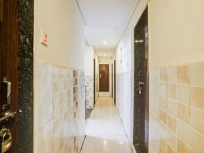 A corridor with tiled walls, a door with a lock, and a light fixture on the ceiling.