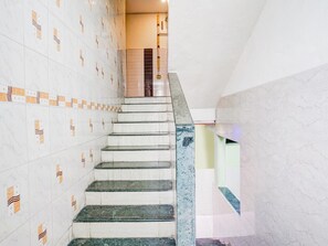 A staircase with marble steps and patterned tiles, leading to a landing with a window and a door.