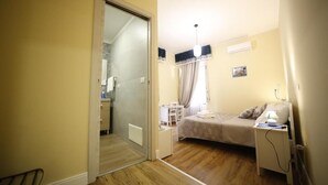 A bedroom with a bed, bedside table, lamp, and a small desk with a chair. - Al Quadrato d'Oro (Catania)