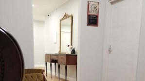 A room with a brown sofa, a wooden dresser, a mirror, and a closed door. - Al Quadrato d'Oro (Catania)