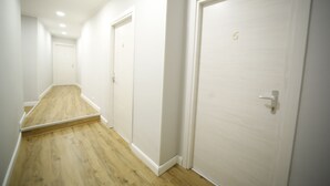 A narrow hallway with wooden flooring, white walls, and closed doors. - Al Quadrato d'Oro (Catania)