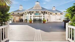 A beachside resort with a covered entrance, a wooden deck, and potted plants. - Steps to the Beach + Resort Pools + Golf | Wild Dunes IOP | 137 Grand Pavilion (Isle Of Palms)