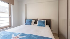 A bedroom with a bed, two pillows, a starfish blanket, a window, and a door. - Chateau Nouvella with balcony by Interhome (Blankenberge)
