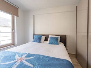 Ein Schlafzimmer mit einem Bett, zwei Kissen, einer Sternenmusterdecke, einem Fenster und einer Tür.