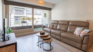 A modern living room with a leather sofa, a wooden coffee table, and a TV on a wooden stand. - Chateau Nouvella with balcony by Interhome (Blankenberge)