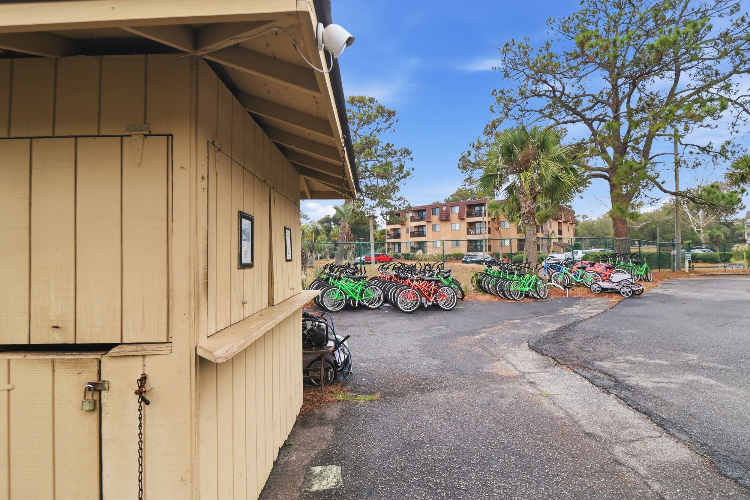 Un edificio con fachada de madera, una cámara de seguridad y un estacionamiento con bicicletas y cuatrimotos.