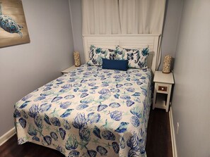 Ein Bett mit Blumenoptik, ein weißes Kopfteil und zwei Nachttische mit Lampen.