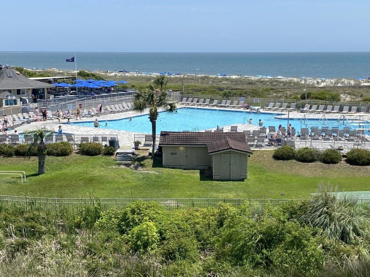 Un espace piscine avec des chaises longues, un petit abri et une vue sur l’océan.