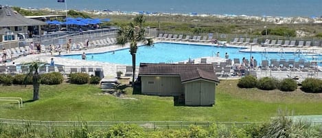 Un espace piscine avec des chaises longues, un petit abri et une vue sur l’océan.