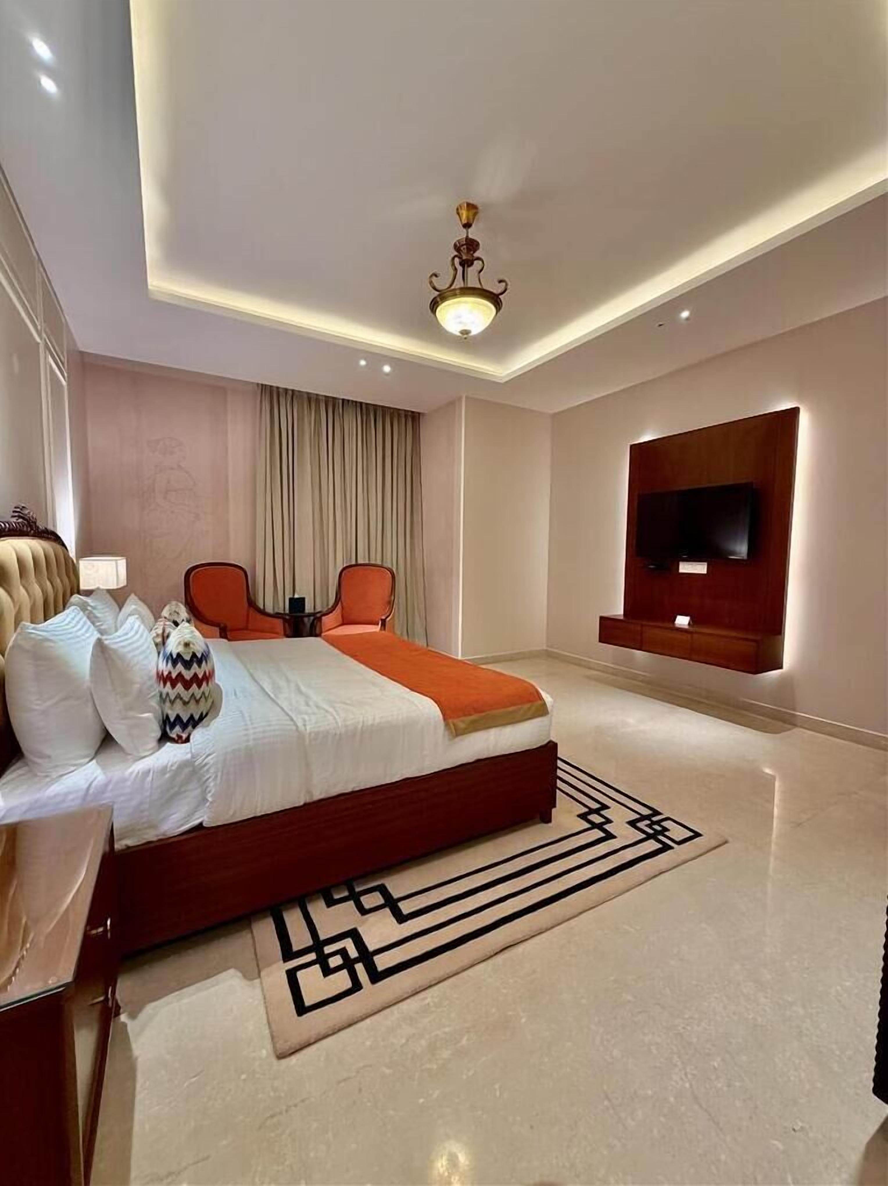 Una habitación de hotel moderna con una cama grande, un televisor de pantalla plana en la pared y una lámpara de techo.
