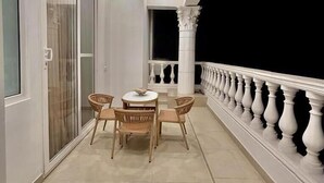 En balkon med et bord og stole, et gelænder og en lampe i loftet.