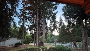A covered outdoor area with a lawn, trees, and a wooden fence. - Wine Country Cottage · King Bed · AC (Woodinville)