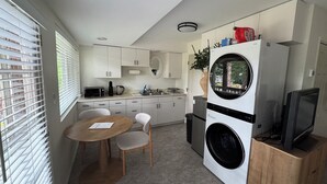 A compact kitchen with a dining area, a washing machine, and a television on a wooden cabinet.