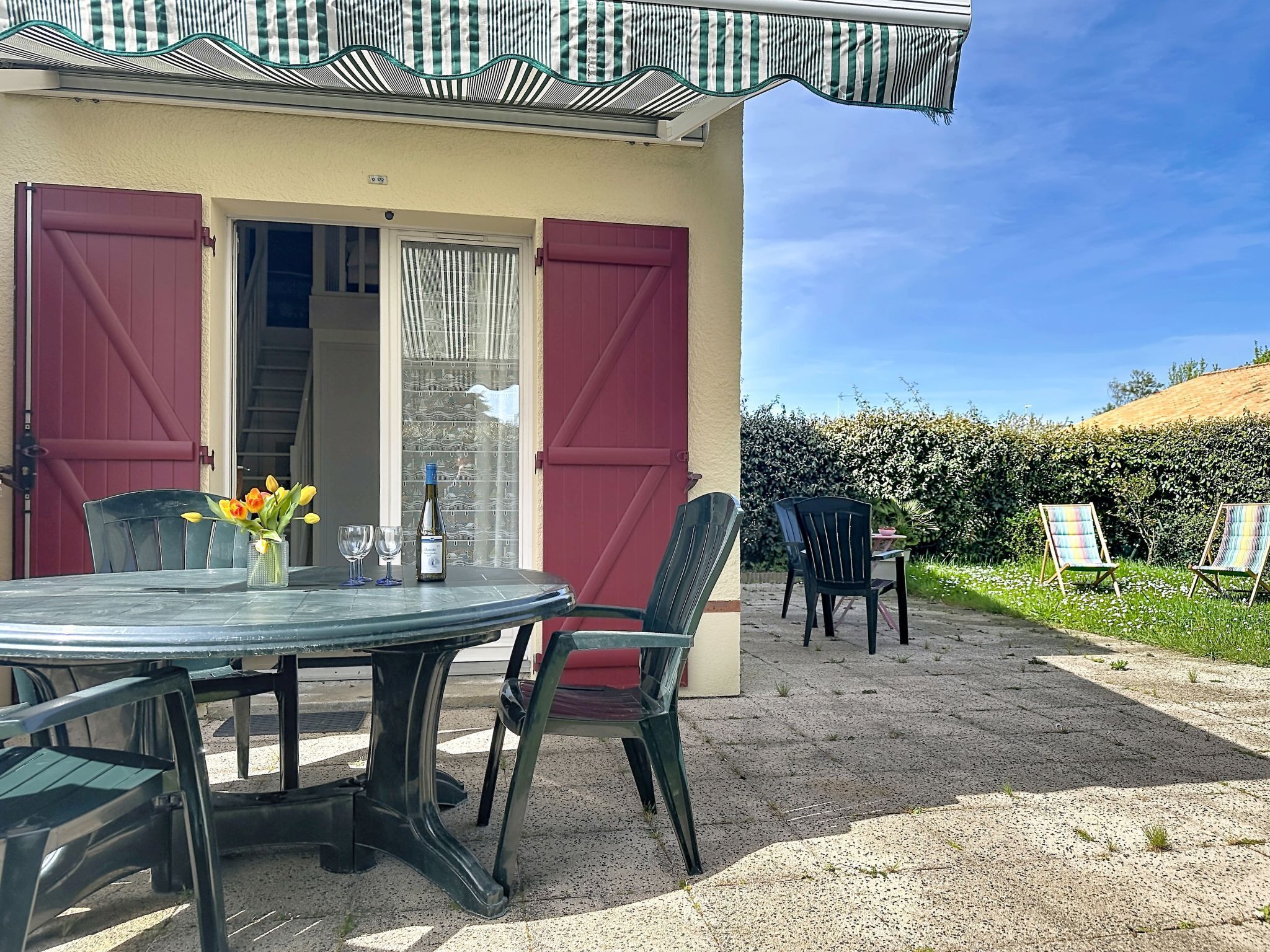 A patio with a table, chairs, and a bottle of wine.