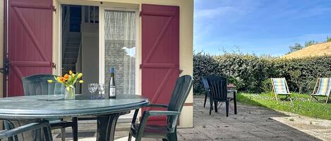 A patio with a table, chairs, and a bottle of wine.