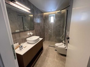 A modern bathroom with a large mirror, a vessel sink, a shower, and a toilet. - Ixia Cozyline Apartment- 101 (Rhodes)