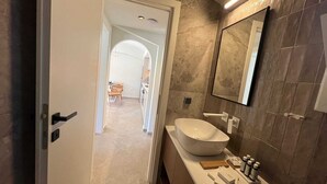 A modern bathroom with a large sink, mirror, and toiletries. - Ixia Cozyline Apartment- 102 (Rhodes)