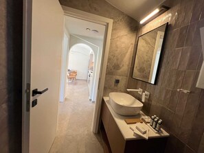 Ein modernes Badezimmer mit einem großen Waschbecken, einem Spiegel und Toilettenartikeln.