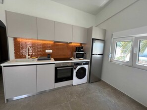Eine kleine Küche mit Waschmaschine, Mikrowelle und Kühlschrank.
