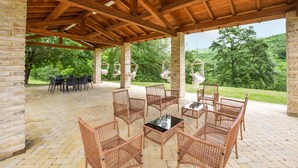 A covered patio area with wicker furniture, hanging hammocks, and a brick floor. - Beautiful home in Monte Santa Maria Tibe (Monte Santa Maria Tibe)