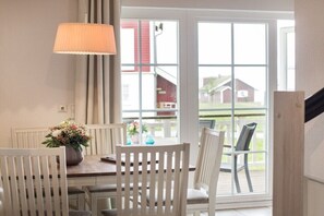 Ein Essbereich mit Tisch, Stühlen, einer Lampe und Blick durch ein großes Fenster.