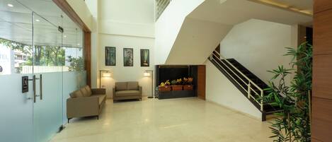 A spacious lobby with a high ceiling, a staircase, and a reception desk.