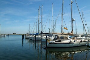 A marina with multiple sailboats docked at wooden piers.