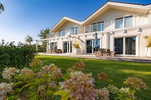 A two-story house with a balcony, large windows, and a well-maintained lawn. - Holiday home with 1 bedroom (Klein Wessek)