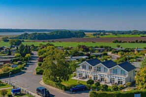 A residential area with houses, a road, and a large field in the background. - Holiday home with 1 bedroom (Klein Wessek)