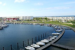 A marina with boats docked, a marina building, and a row of residential buildings in the background. - Trumann "Laughing Gull" (Fehmarn (Südstrand))