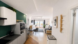 Eine moderne Küche mit weißen Schränken, einer schwarzen Arbeitsplatte und einem Essbereich mit grauem Stuhl und Tisch.