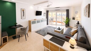 Ein modernes Wohnzimmer mit Sofa, Esstisch, Fernseher und einem Balkon mit Blick.