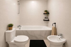 Ein Badezimmer mit Toilette, Bidet, Badewanne und Ablagen für Toilettenartikel.