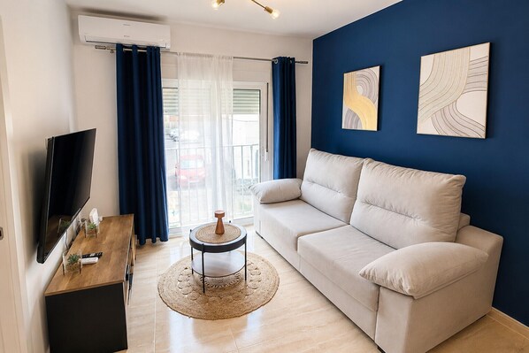 Ein Wohnzimmer mit einer Couch, einem Fernseher, einem Couchtisch und Kunstwerken an der Wand.