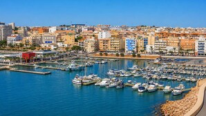 A marina with numerous boats docked, surrounded by a coastal cityscape with buildings. - Apartment for 3, a short walk from the beaches (Roquetas de Mar)