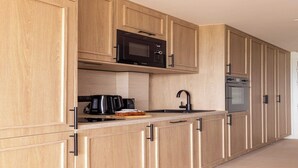 A modern kitchen with wooden cabinets, a microwave, a coffee maker, and an oven. - 1BDR/4P flat with stunning sea views (Antibes)