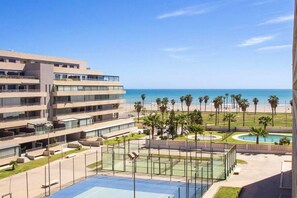 Ein modernes Hotel mit Pool, Tennisplätzen und Meerblick.