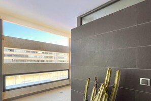 Ein modernes Interieur mit Balkon, grauen Fliesenwänden und einer Kakteendekoration.